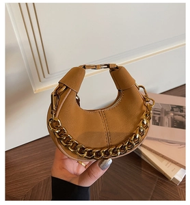 Détail d'un sac demi-lune en cuir marron avec chaîne dorée épaisse et fermoir doré