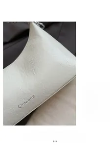 Close-up of white crinkled leather texture and silver chain on small crossbody bag