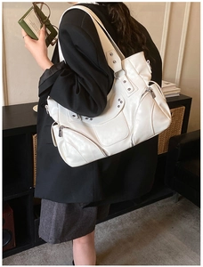 Vue détaillée du sac à bandoulière blanc avec clous métalliques et détails zippés