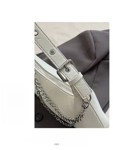 Detail of ivory faux leather handbag showing silver buckle and decorative chain strap