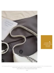 Detail of white faux leather shoulder bag with silver chain and adjustable buckle strap