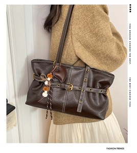 Detail of dark brown tote bag with vintage leather texture and heart tassel charm