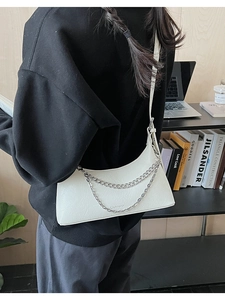 White pleated leather shoulder bag with double silver chain detail on office desk