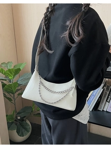 Detail of white lychee leather dumpling bag with decorative double silver metal chains
