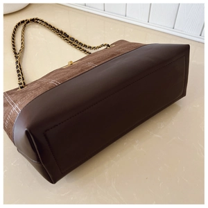 Detail of retro tote bag with brown patchwork design, gold chain and twist lock closure