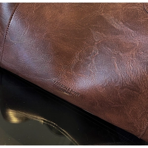 Detail of dark brown leather tote bag showing fine stitching and fashion brand logo