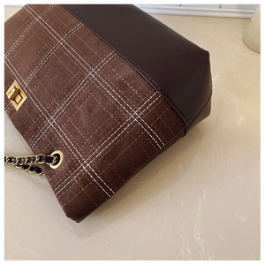 Detailed view of vintage tote with brown leather, suede plaid panel, and gold metal lock