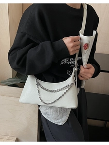 Detail of white pleated leather shoulder bag with double metal chains and long strap