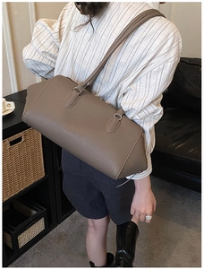 Detailed view of brown lychee-textured leather tote bag featuring slim shoulder straps