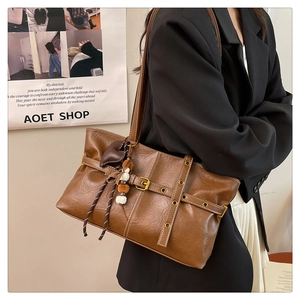 Brown faux leather tote bag with heart charm shown on model in black blazer