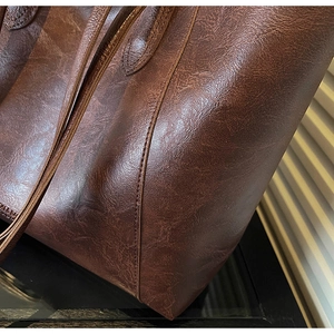 Detail of vintage oil wax leather texture and reinforced stitching on brown tote bag