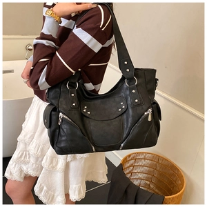 Détail du grand sac cabas noir style motard avec clous et anneau porté par un mannequin