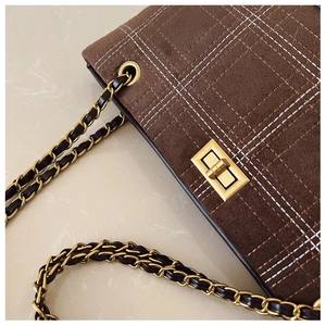 Close-up of brown plaid suede tote bag with gold metal twist lock and chain strap