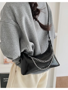 Detail of black glossy crescent bag with silver dual chains and white logo print