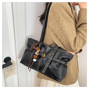 Close-up of black retro tote bag with white contrast stitching and decorative pendants