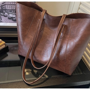 Detail of dark brown tote bag with oily leather texture and metallic zipper closure