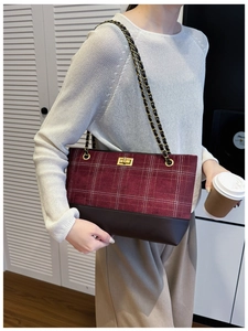 Detail of burgundy plaid tote bag with gold metal twist lock and leather chain strap