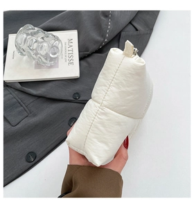 Detailed side view of beige quilted puffy cloud handbag with soft padded texture