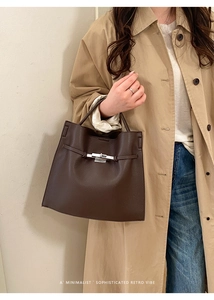 Close-up of a retro dark brown litchi pattern leather handbag with silver twist lock
