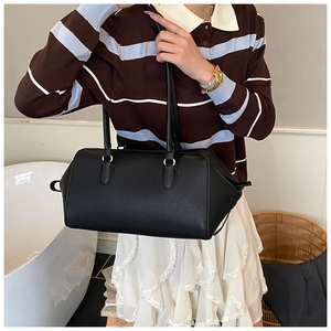 Detail of black pebbled leather tote bag with silver hardware and elongated top handles