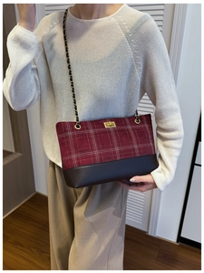 Detail of burgundy plaid shoulder bag with dark brown leather and golden metal clasp