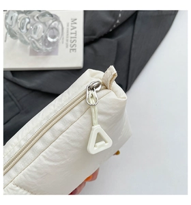 Close-up of a silver zipper with a unique white triangular pull on a quilted pouch bag