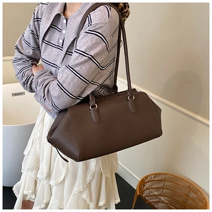 Detail of dark brown lychee textured leather shoulder bag with silver metal ring hardware