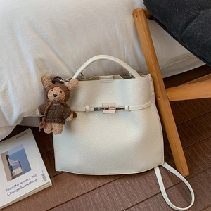 Detail of cream lychee leather bucket bag featuring a silver lock and cute bear charm
