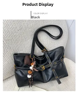 Detail of black tote bag featuring white contrast stitching and gold buckle hardware