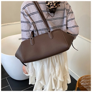 Deep brown lychee grain leather tote bag worn as a shoulder bag on a female model