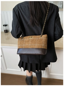 Detail view of the quilted brown suede stitching and golden twist lock on tote bag