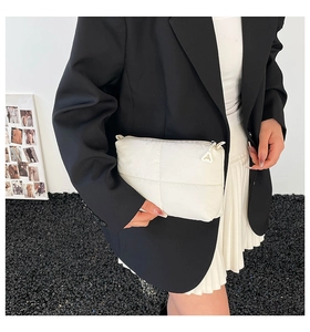 Detailed view of a white quilted crossbody bag with soft puffer texture and modern zipper