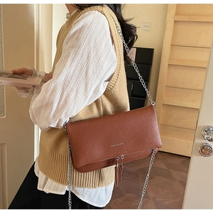 Brown lychee leather chain bag with Manos & Co logo and dual tassel zipper detail