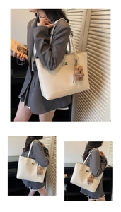 Detail view of cream leather tote bag with metallic logo and plush bear accessory