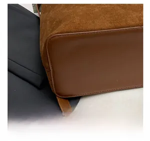 Macro shot of precise stitching on vintage brown suede and smooth leather tote bag base