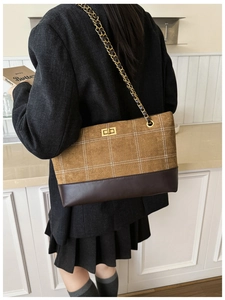Detail of vintage brown suede tote with contrast stitching and golden chain strap