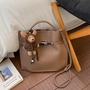 Macro shot of brown pebble grain leather bucket bag with silver lock and bear charm