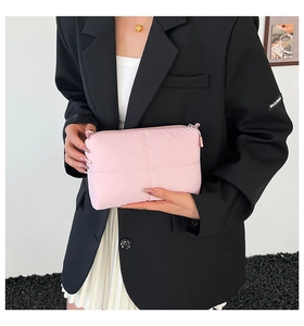Pink quilted nylon pouch with square stitching held by a model in a black suit