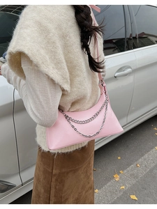 Detail of pink PU leather underarm bag with silver chains in a street style setting