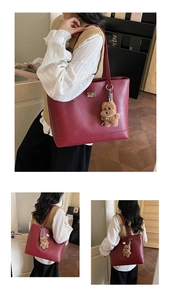 Detail view of burgundy leather tote bag with plush puppy charm and golden metal nameplate