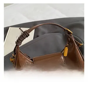 Detail of dark brown crescent bag with glossy oil wax leather and wrapped handle grip