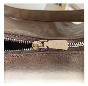 Gros plan sur la fermeture éclair en métal argenté d'un sac bandoulière en cuir marron