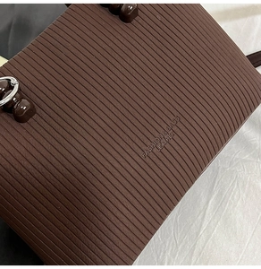 Détail du sac en cuir marron foncé montrant la texture horizontale et les ferrures argent