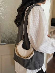 Sac hobo demi-lune ivoire chic avec chaîne dorée et bandoulière porté par un mannequin