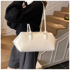 Chic beige pebbled leather shoulder bag shown from a side-rear angle on a model