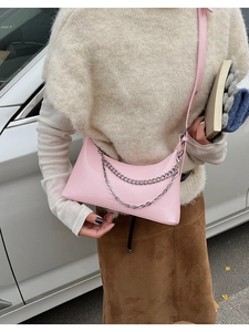 Detail of light pink PU leather underarm bag with silver chain straps and embossed logo