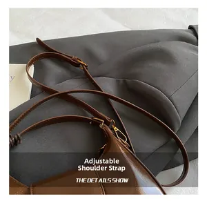Detail view of the adjustable glossy leather shoulder strap with gold-tone hardware buckles