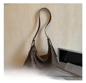 Détail du grand sac bandoulière en cuir marron foncé avec pompon et fermeture éclair en métal