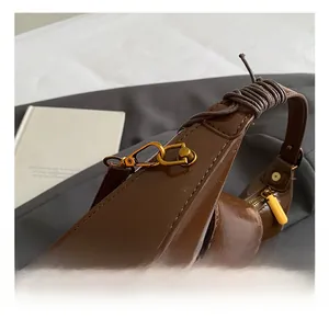 Detail of high-quality metal hook and oily brown leather texture on handbag