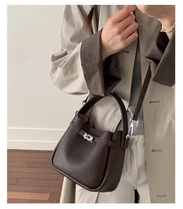 Détails de la texture du cuir litchi marron et du fermoir en métal sur le sac seau